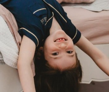 Klein meisje dat een donkerblauwe pyjama draagt en ze is gelukkig